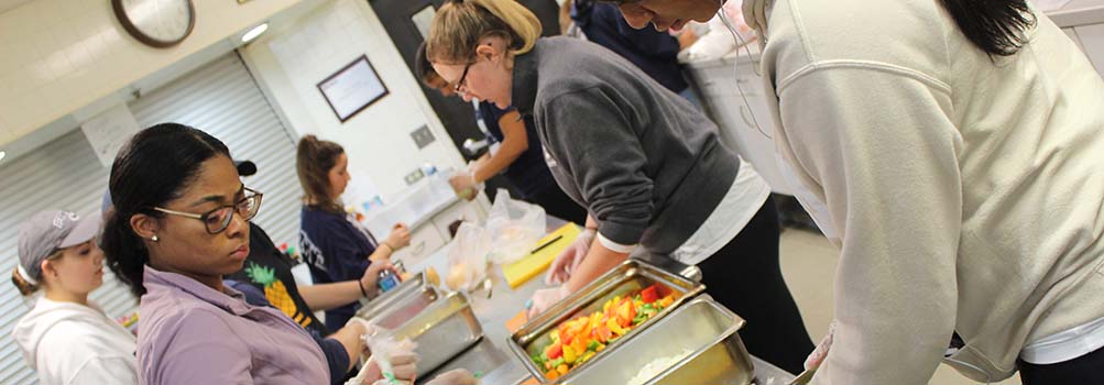 Students volunteer in a kitchen, preparing meals