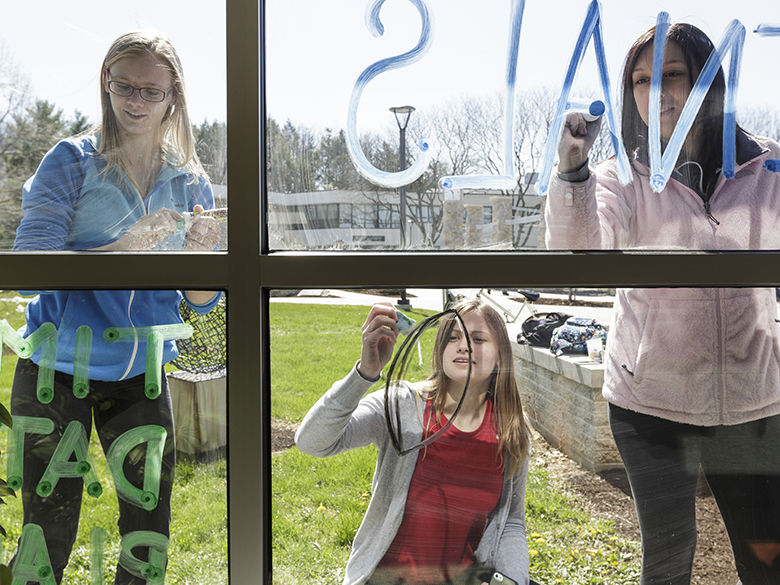 Students working on writing messages on Thun Library windows